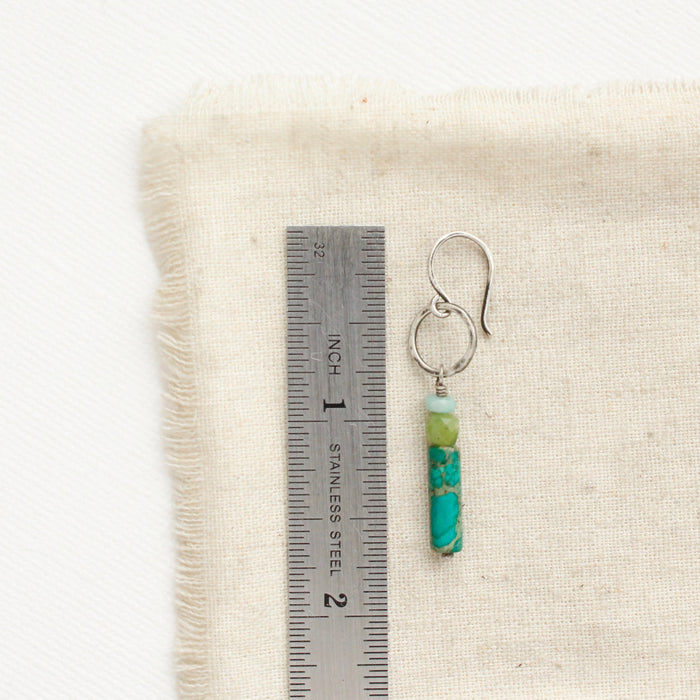 A meadow sydney hoop earring next to a ruler for size reference.
