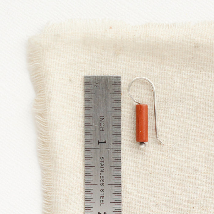 A red jasper lobe hugger earring next to a ruler for size reference.