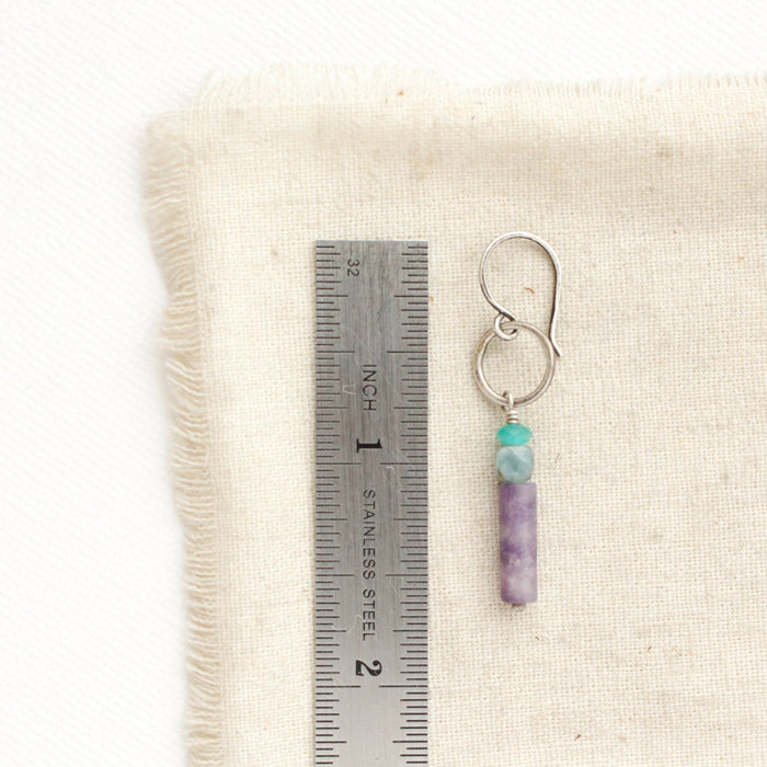 A twilight sydney hoop earring next to a ruler for size reference.