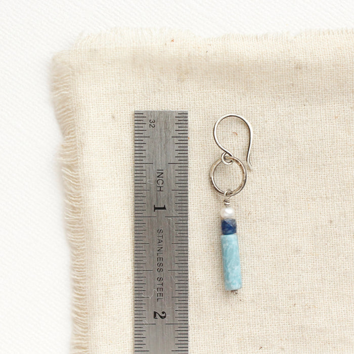 A mirage sydney hoop earring next to a ruler for size reference.