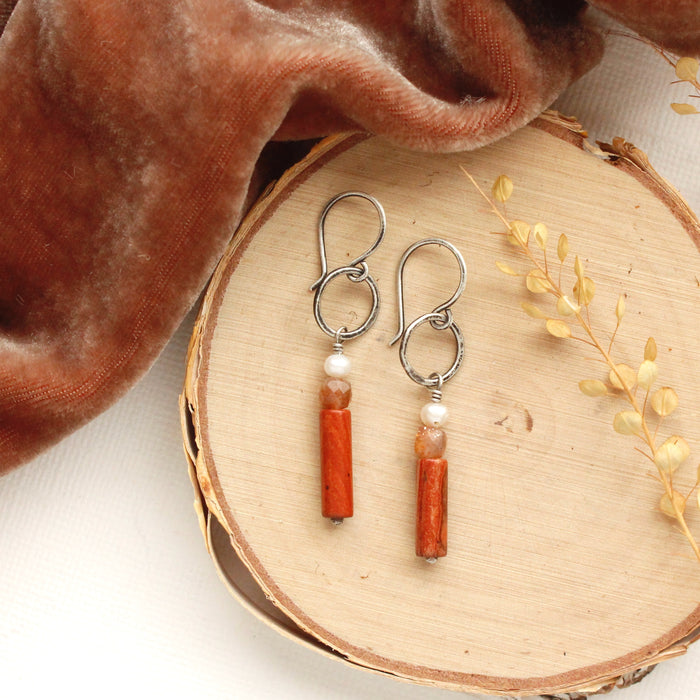 The canyon sydney hoop earrings styled on wood with orange velvet and dried grass.