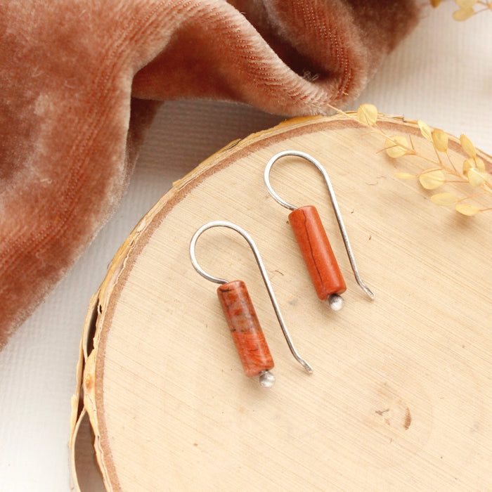 The red jasper lobe hugger earrings styled on wood with orange velvet.