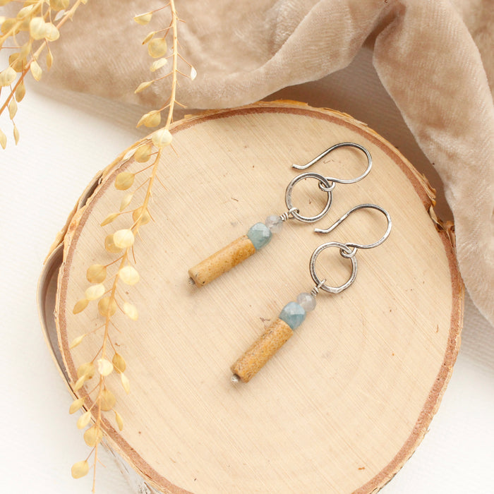 The oasis sydney hoop earrings styled on wood with tan velvet and dried grass.