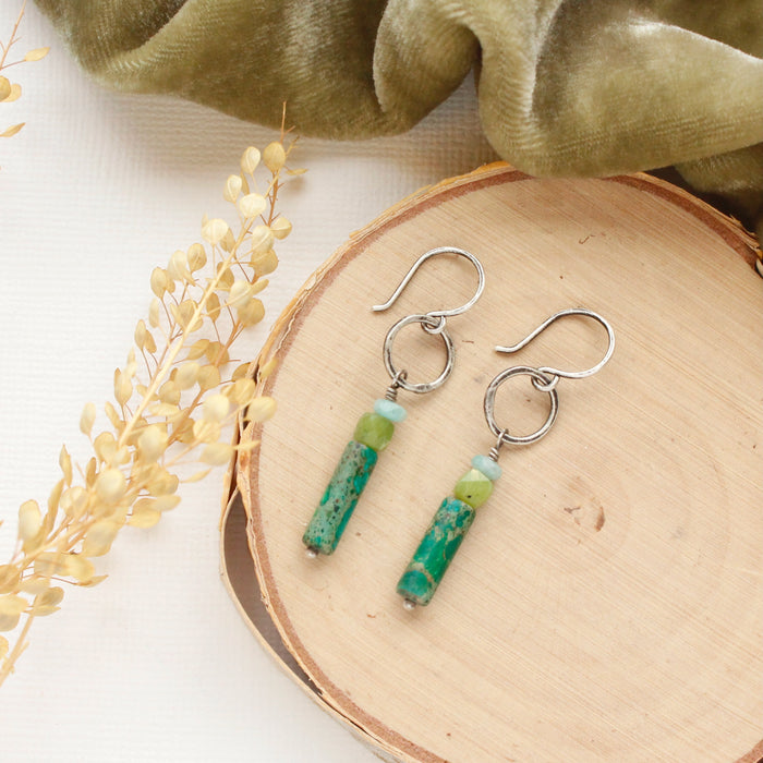 The meadow sydney hoop earrings styled on wood with green velvet and dried grass.