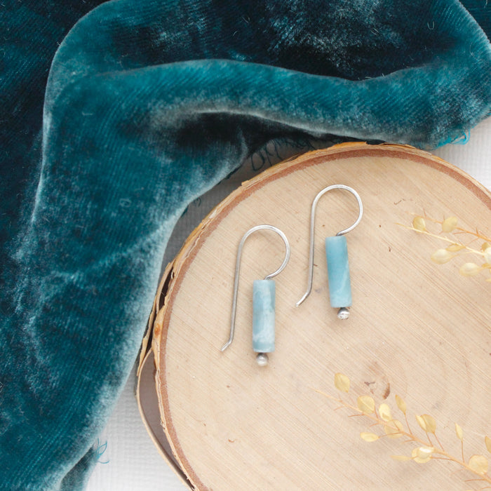 The larimar lobe hugger earrings styled on wood with blue velvet and dried grass.