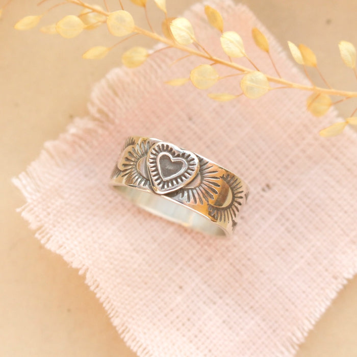 The layered silver band ring styled on pink linen and a tan plate with dried grass