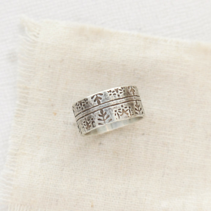 The nordic stamped band ring styled on tan linen