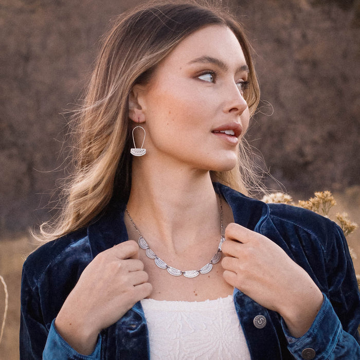 A model wearing the asmi long loop earrings and asmi full collar necklace