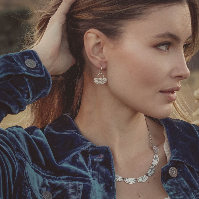 A model wearing the asmi short loop silver earrings and matching necklace