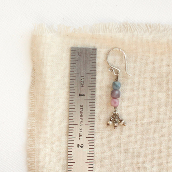 A stacked sapphire earring next to a ruler for size reference