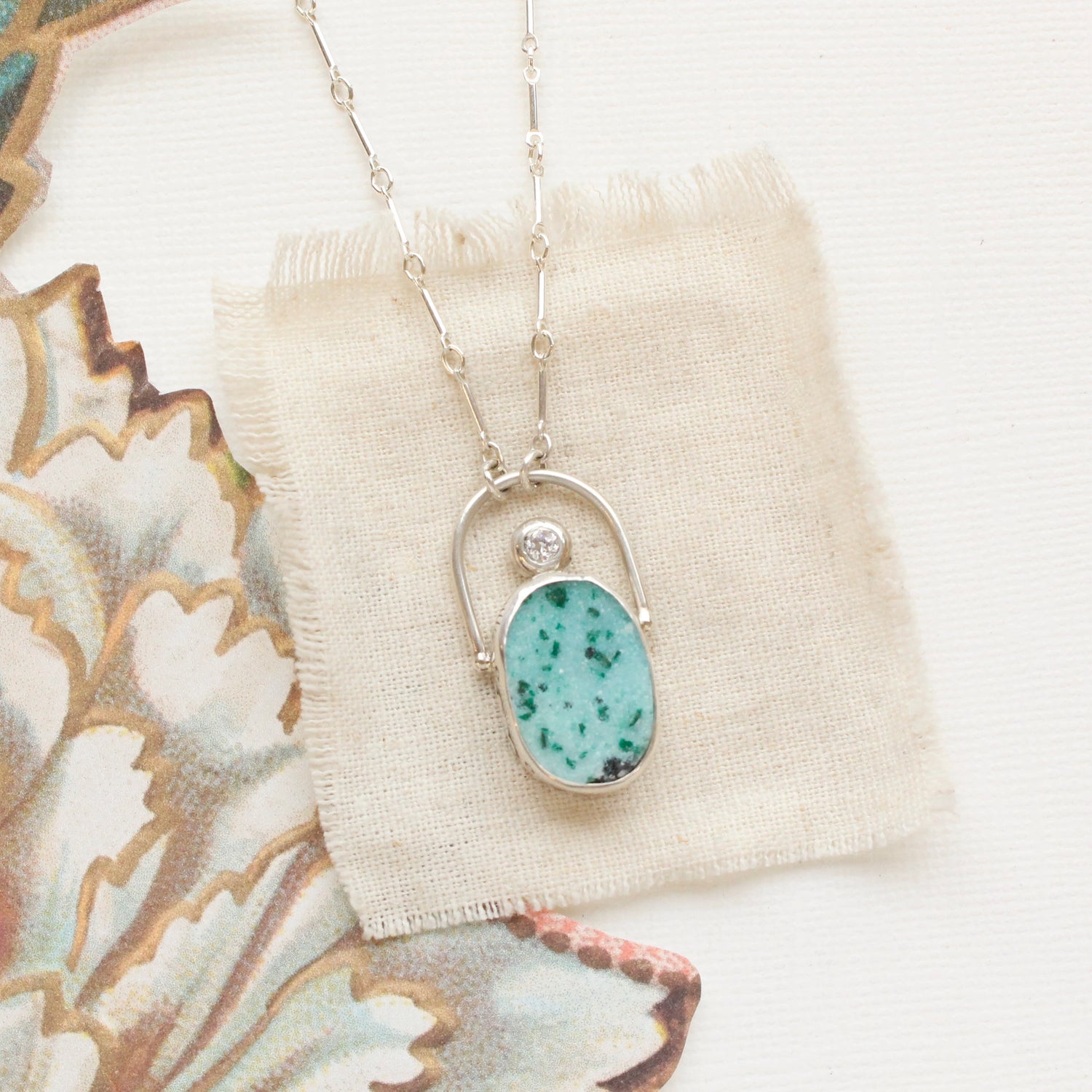 The gem silica and cz necklace styled on tan linen
