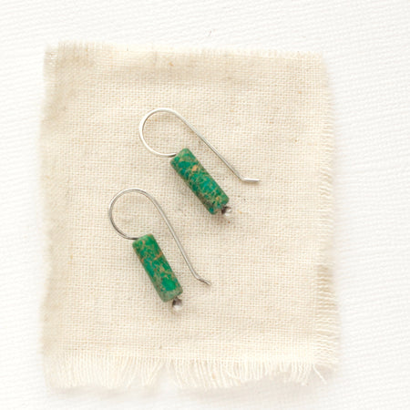The green sediment jasper lobe hugger earrings styled on tan linen