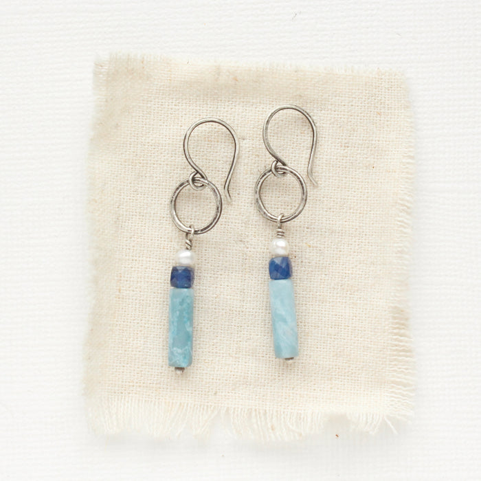 The mirage sydney hoop earrings styled on tan linen.