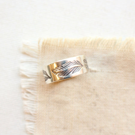 The stamped feather band ring styled on tan linen