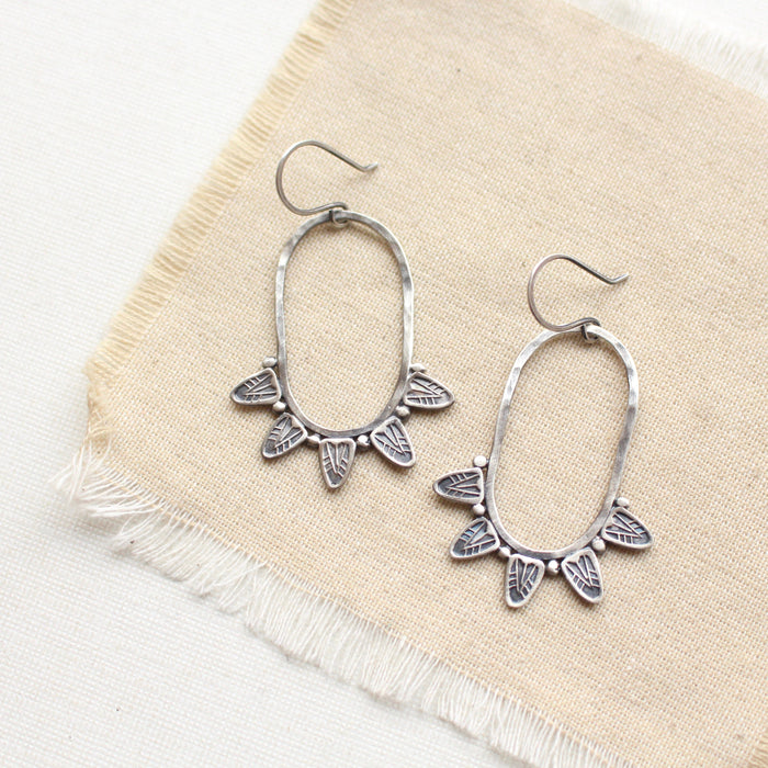 The tribal inspired feathered hoop earrings styled on tan linen