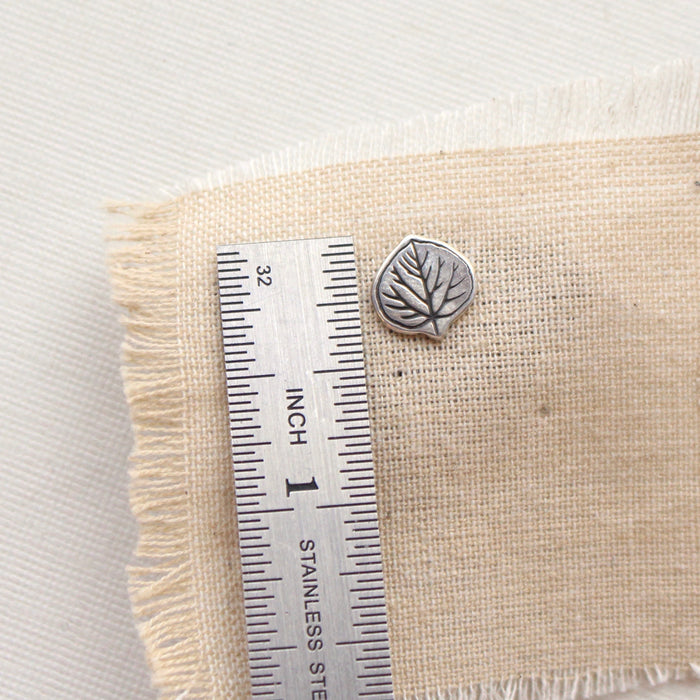 An aspen leaf post earring next to a ruler for size reference