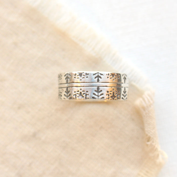 The nordic stamped band ring is styled on tan linen