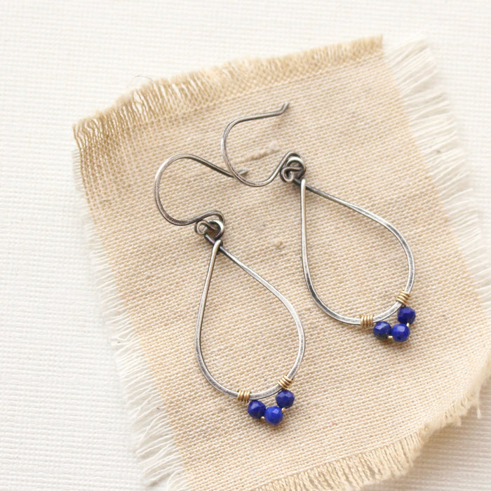 The southwest lapis wrapped teardrop mixed metal hoop earrings styled on tan linen