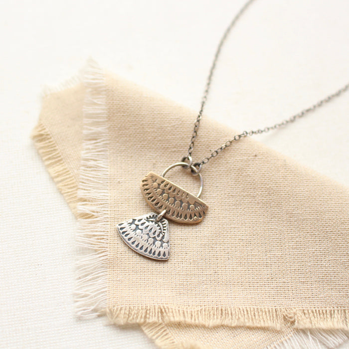 The stamped silver and bronze asmi duo necklace styled on tan linen
