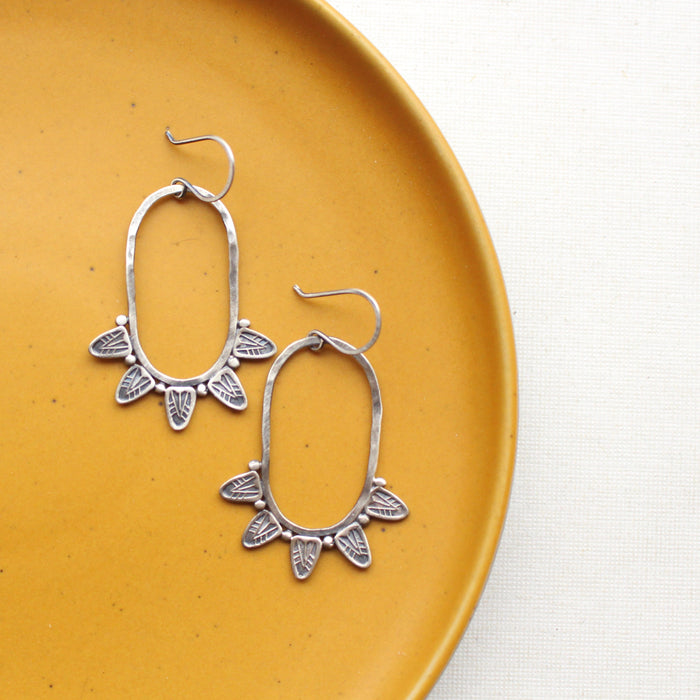 The tribal inspired feathered hoop earrings styled on a yellow plate