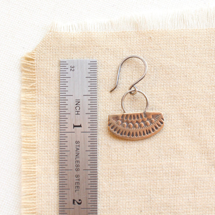 An asmi short loop mixed metal earring styled next to a ruler for size reference