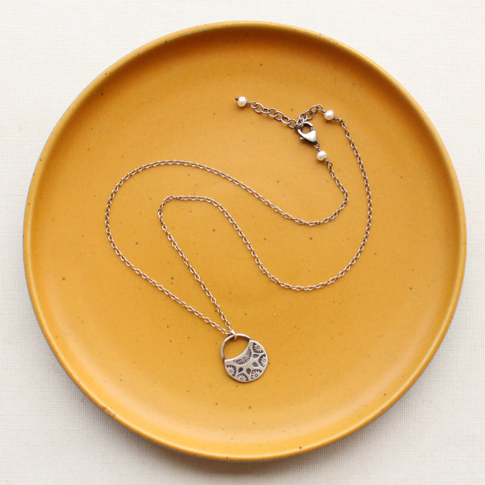 The midnight bloom necklace styled on a yellow plate to show the adjustable lobster clasp closure