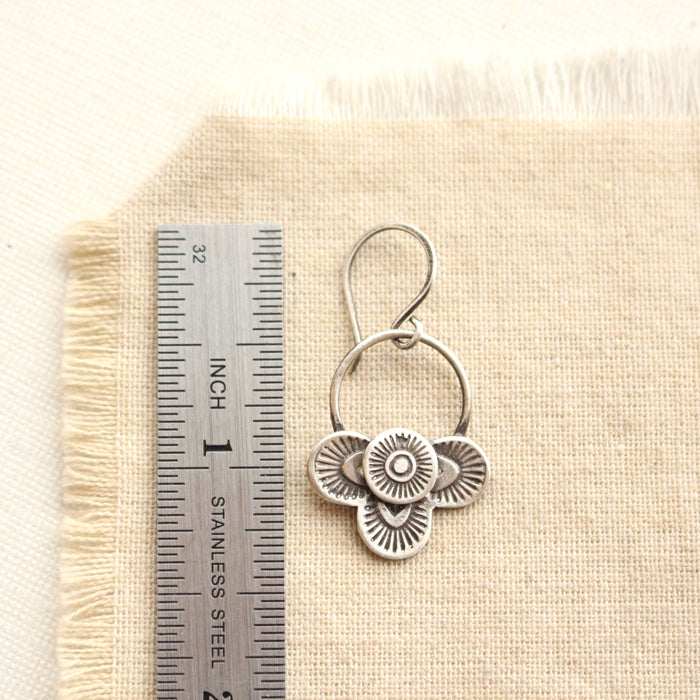 A layered talara earring next to a ruler for size reference