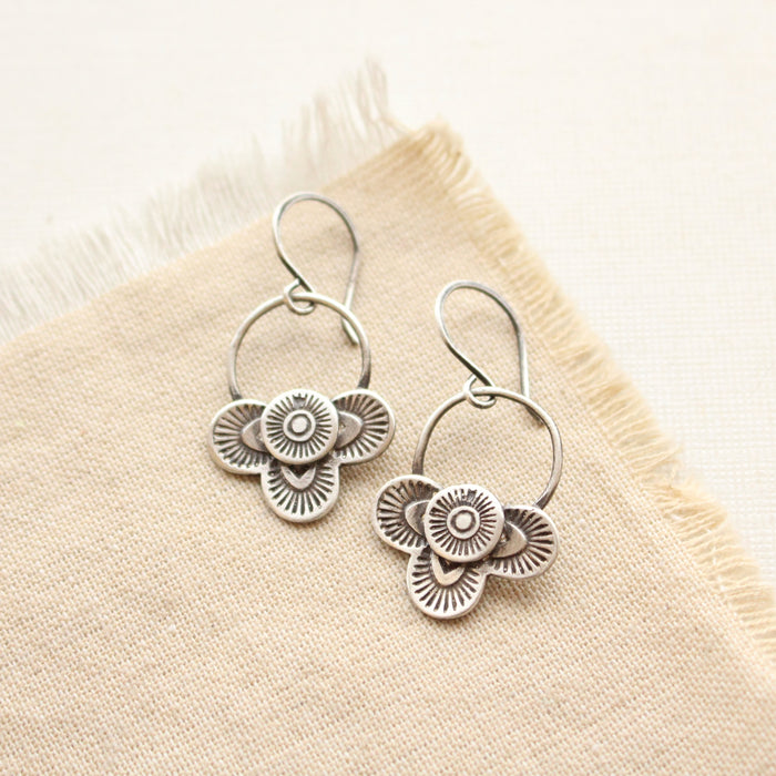 The layered talara loop earrings styled on tan linen