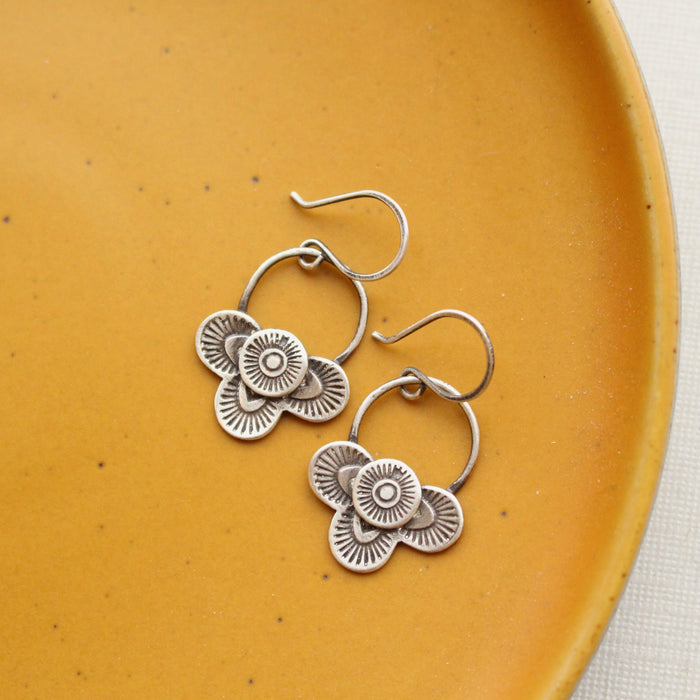 The layered talara loop earrings styled on a yellow plate