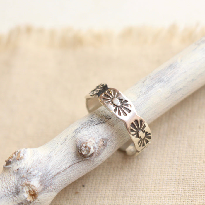 The scalloped silver ring styled on a stick and tan linen