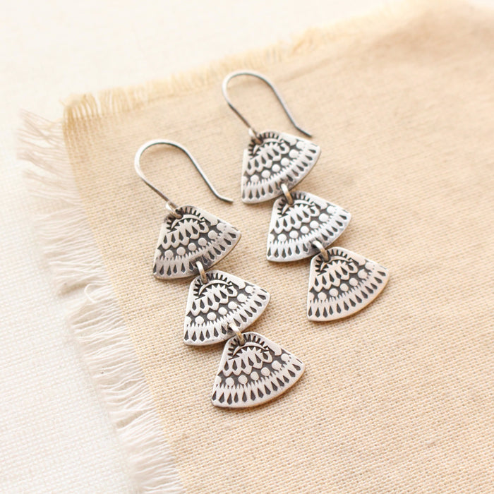 The asmi trio triangle long earrings styled on tan linen