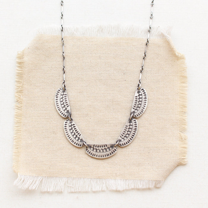 The asmi 5 collar necklace styled on tan linen