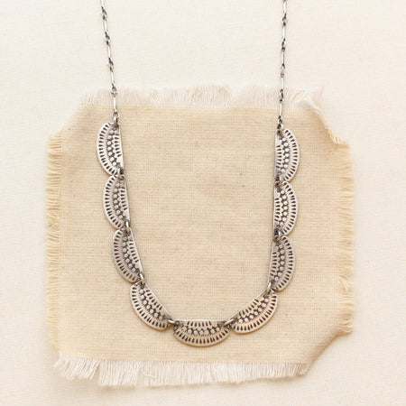 The asmi silver full collar necklace styled on tan linen