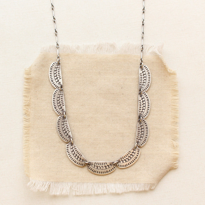 The asmi silver full collar necklace styled on tan linen