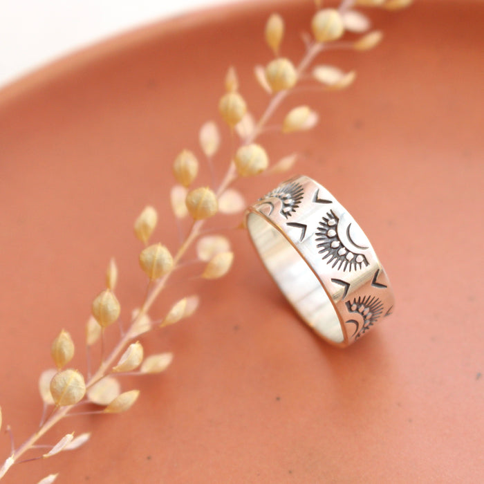 The indian sun stamped band ring styled on a red plate with dried grass