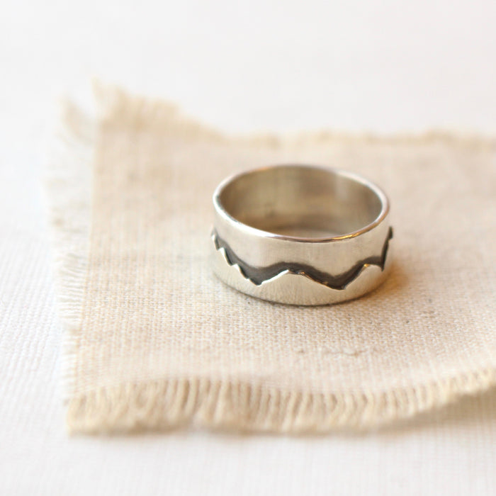 The layered silver mountain band ring styled on tan linen