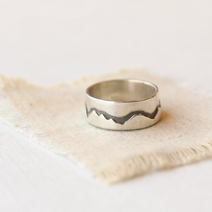 The layered silver mountain band ring styled on tan linen