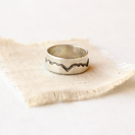 The layered silver mountain ring styled on tan linen