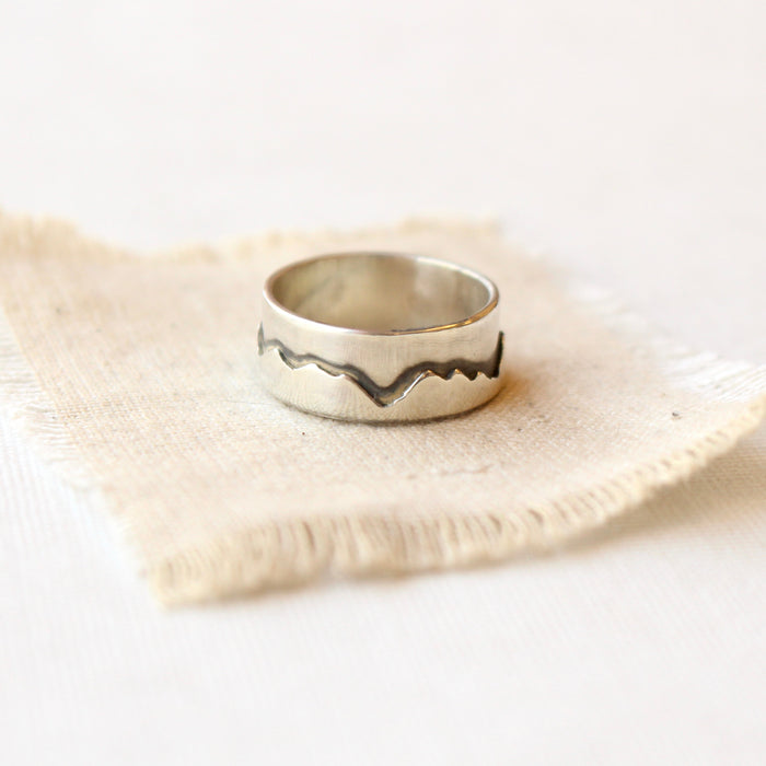 The layered silver mountain ring styled on tan linen