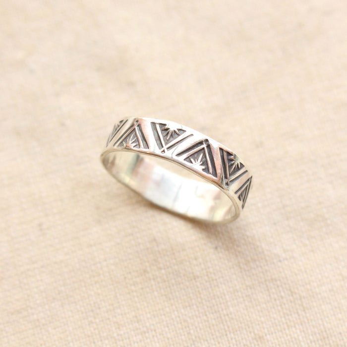 The stamped triangle silver ring styled on tan linen