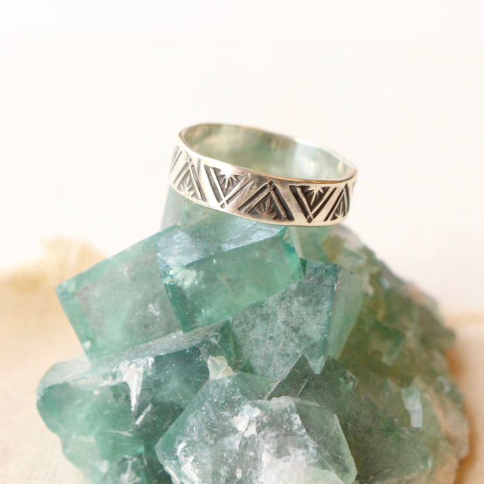 The stamped triangle silver ring styled on a green crystal and tan linen