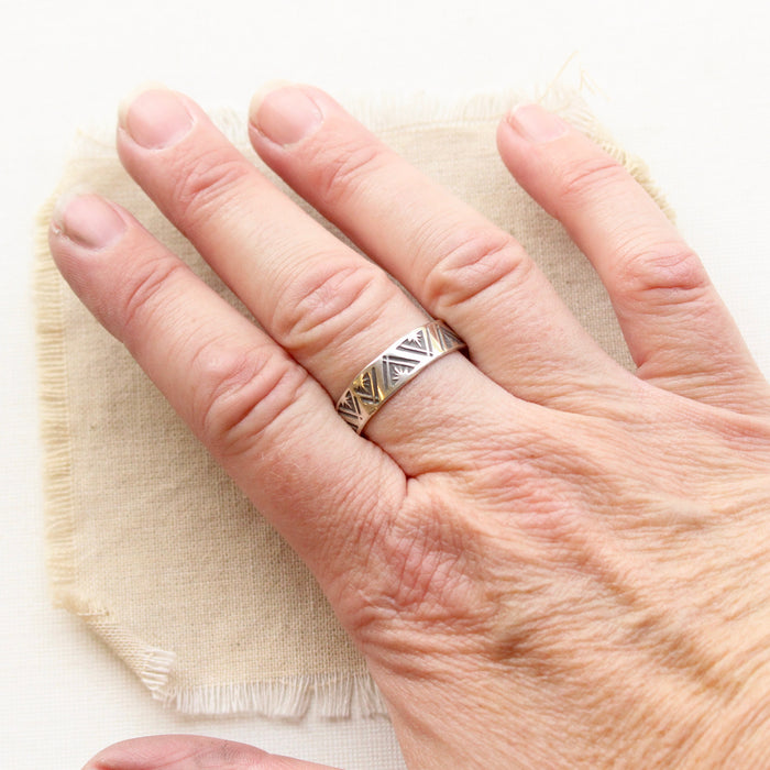 The stamped triangle silver ring styled on a hand to show size reference