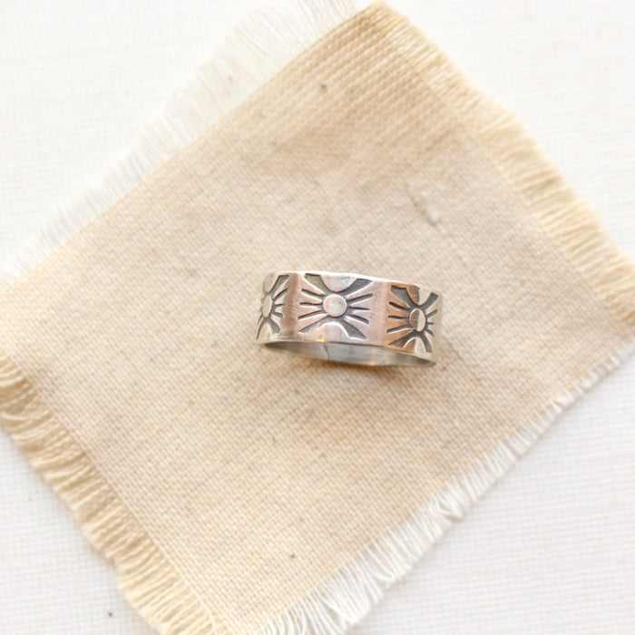 The industrial stamped silver band ring styled on tan linen