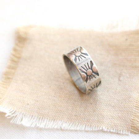 The industrial stamped silver band ring styled on tan linen