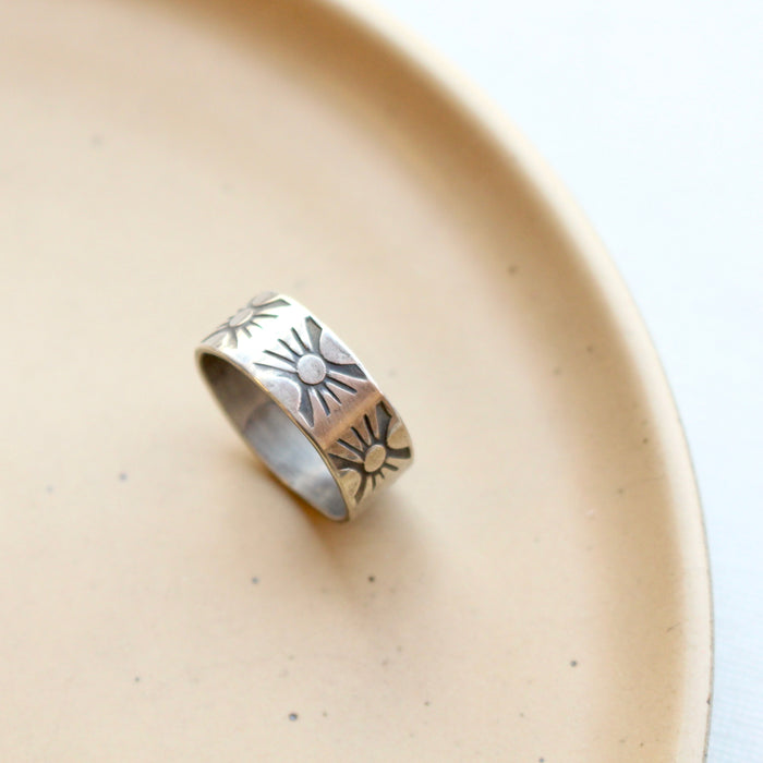 The industrial stamped silver band ring styled on a tan plate
