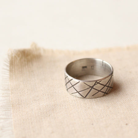The embrace the chaos silver band ring styled on tan linen