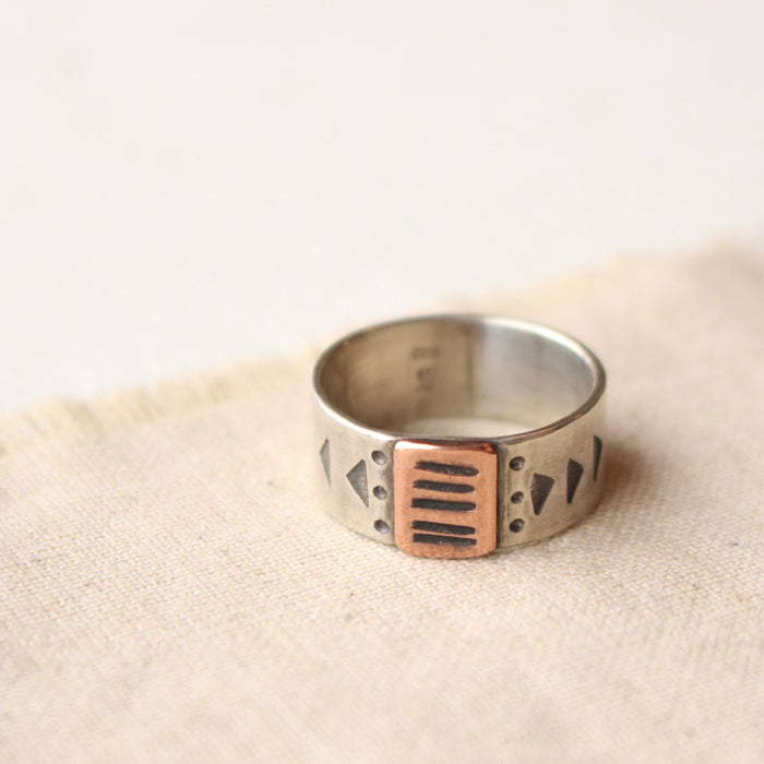 The rustic, southwest bronze and silver stamped band ring styled on tan linen