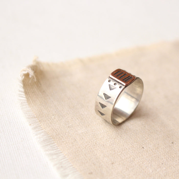 The southwest stamped bronze and silver band ring styled on tan linen