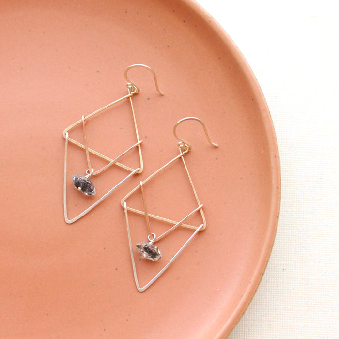 The triple triangle herkimer diamond earrings styled on a red plate