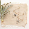 The triple triangle herkimer diamond earrings styled on tan linen with an air plant